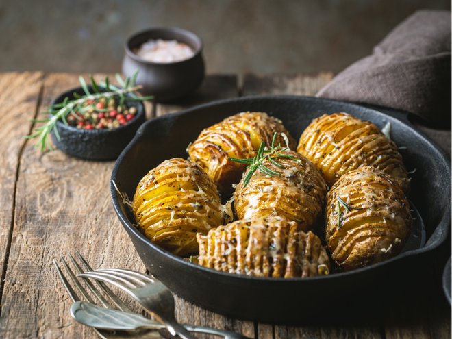 Baked hasselback potatoes with cheese, garlic and greens